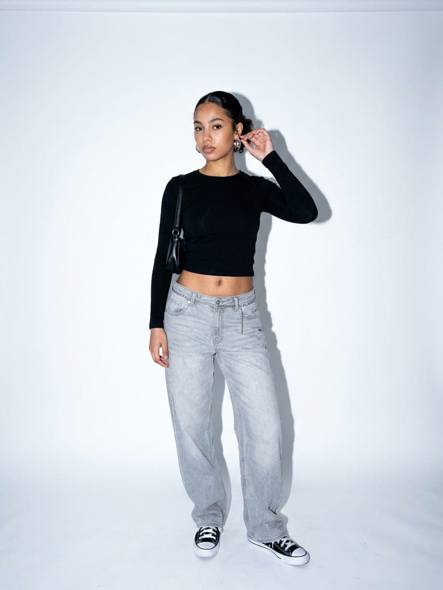 Featured outfit: black long-sleeve crop top, baggy grey jeans and black-and-white sneakers, full body